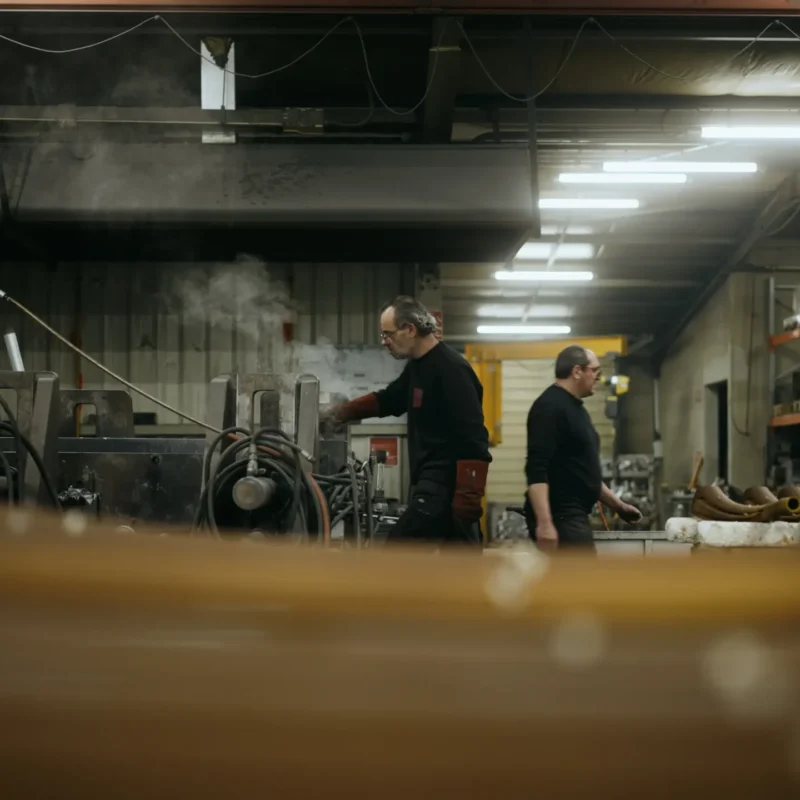 Vue d'ensemble de l'atelier de fonderie, opérateurs au travail dans la vapeur ambiante