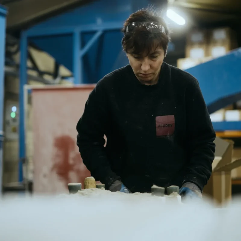 Opératrice façonnant un moule en sable à son poste de travail dans l'atelier de fonderie