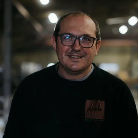Portrait souriant d'un opérateur à lunettes au sein de l'atelier de fonderie aluminium