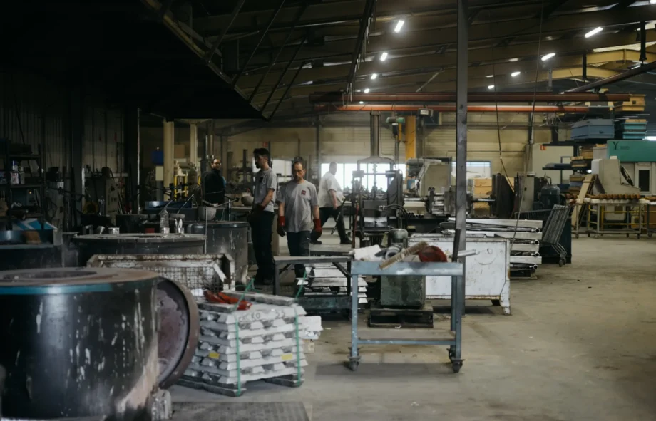 Vue d'ensemble de l'atelier avec opérateurs, lingots empilés et postes de moulage