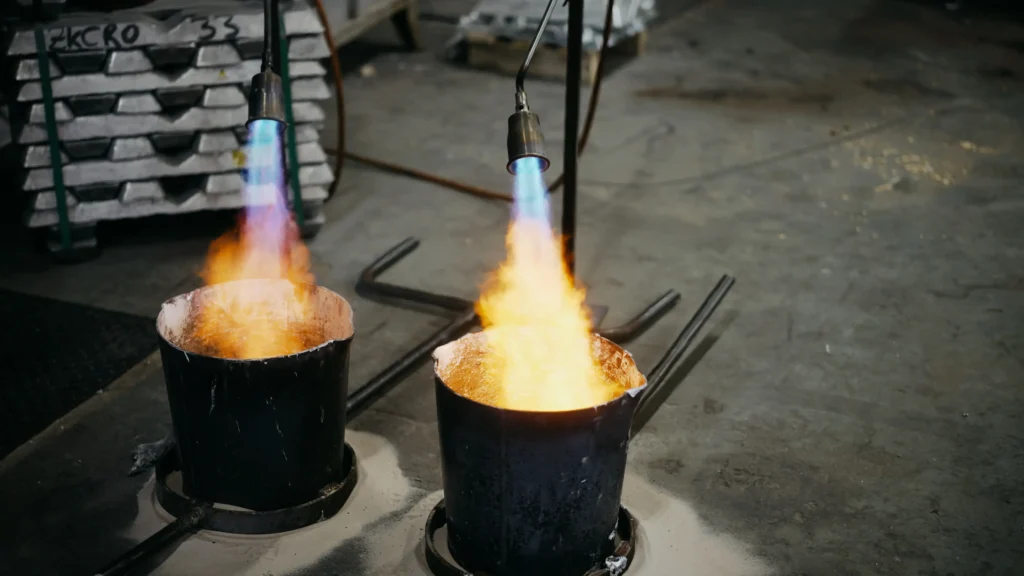 Deux poches préchauffées au brûleur, flammes orangées et lingots rangés à l'arrière