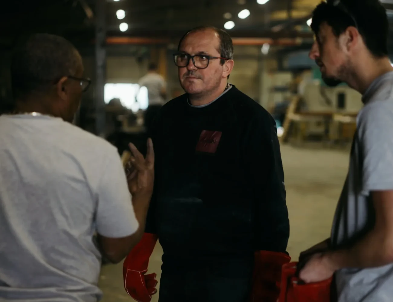 Trois collaborateurs de la fonderie échangeant ensemble dans l'atelier de production