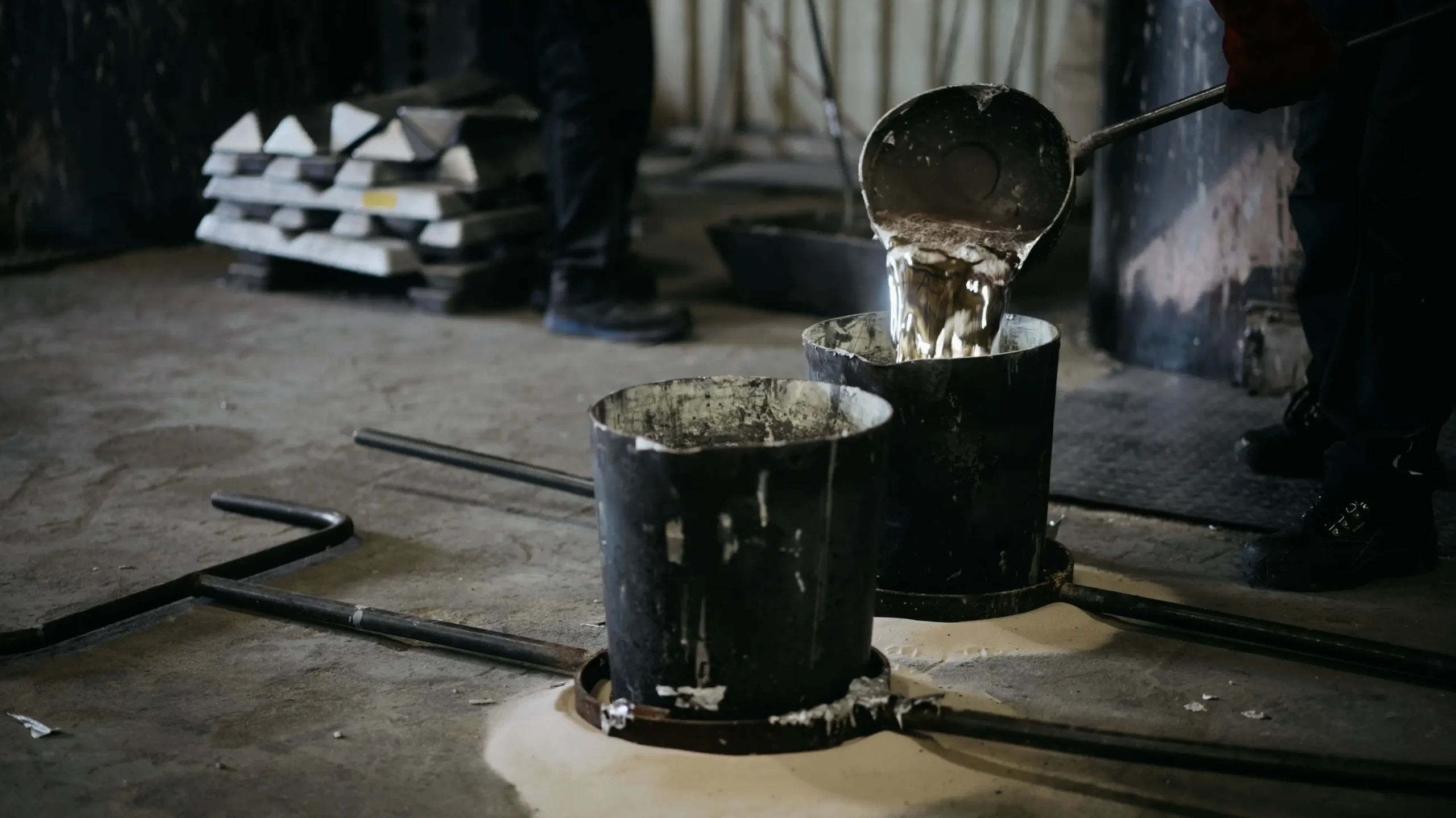 Remplissage d'un creuset avec de l'aluminium fondu, lingots bruts posés à proximité