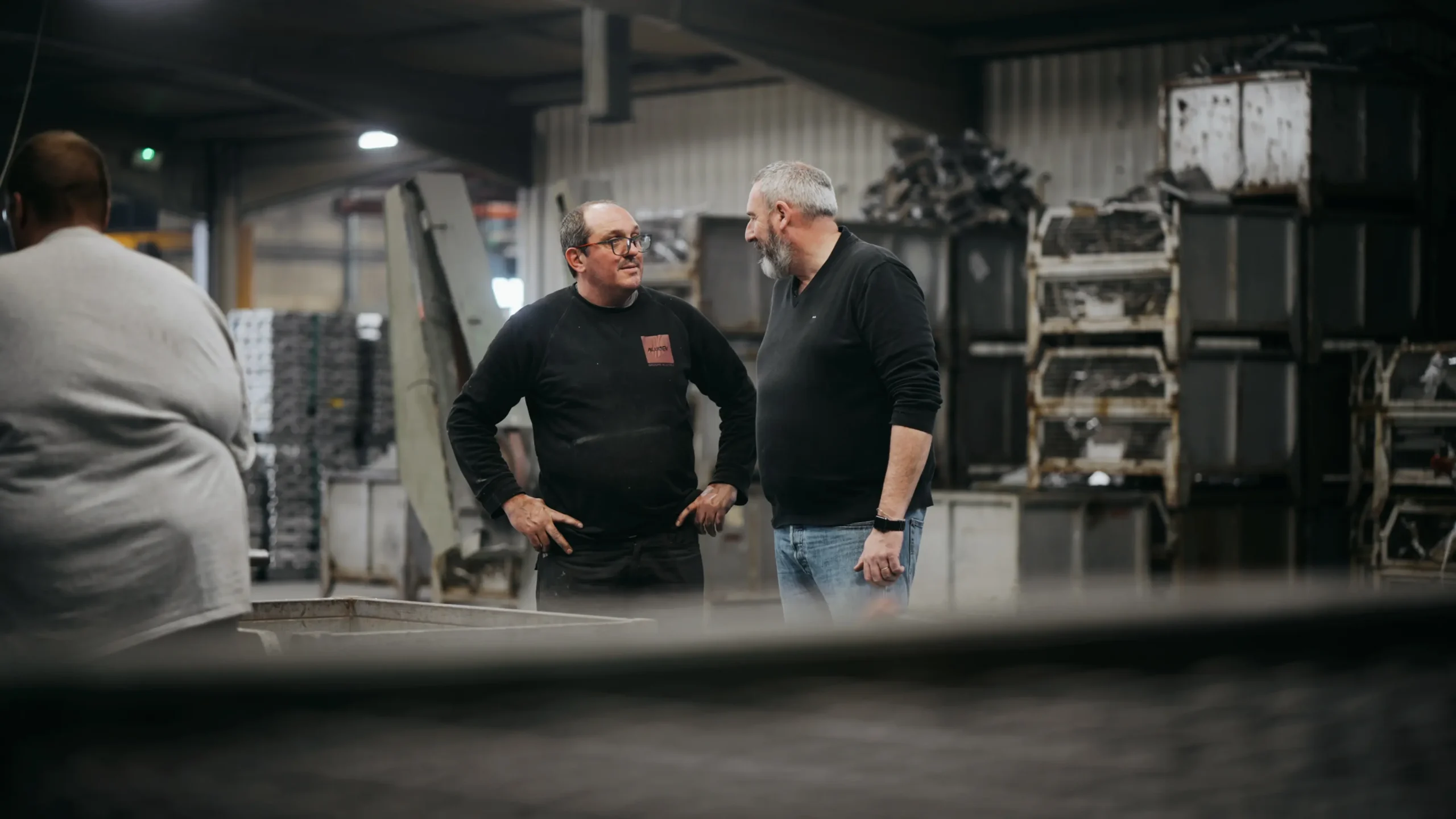 Deux responsables échangeant dans l'atelier de la fonderie aluminium au premier plan