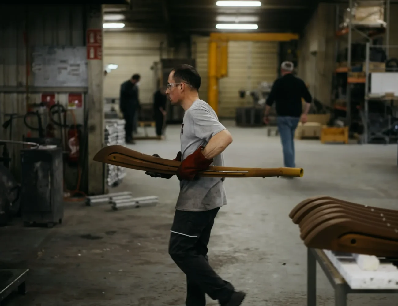 Ouvrier transportant une longue pièce métallique à travers l'atelier de fonderie