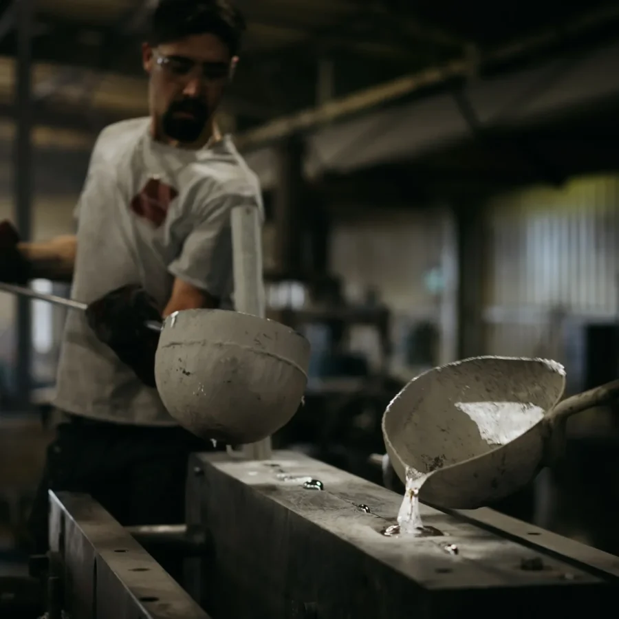 Opérateur coulant le métal en fusion à la louche dans un moule sablé de l'atelier